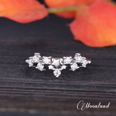 three diamond studs on top of a wooden table next to an orange flower arrangement