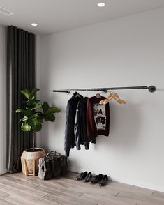 an empty room with clothes hanging on the rack and shoes next to it in front of a window