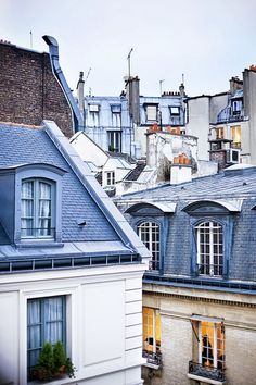 the roofs of several buildings are covered in blue tints and windows with white shutters