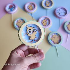 a hand is holding a cupcake topper with an image of a bird on it