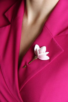 a woman in a pink suit with a flower on her lapel