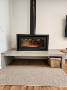 a fire place in the middle of a room with wood floors and a rug on the floor