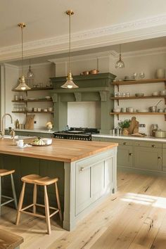 a large kitchen with wooden floors and green cabinetry on the walls, along with two stools