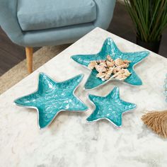 three star shaped dishes sitting on top of a marble table next to a blue chair