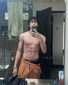 a shirtless man taking a selfie in front of a mirror with his cell phone