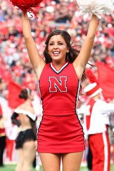 a cheerleader is holding her pom - poms in the air at a football game