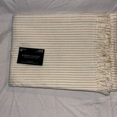 a white and gold striped blanket with a black tag on it