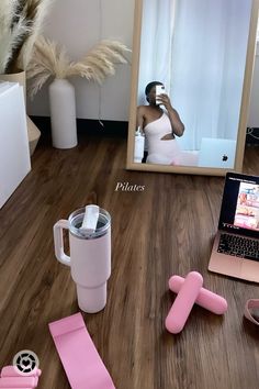 a woman taking a selfie in front of a mirror with her laptop and pink accessories