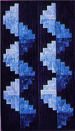 a black and blue quilt with white squares on the top, in front of a dark background