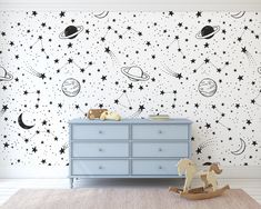 a child's room with stars and planets on the wall, including a rocking horse