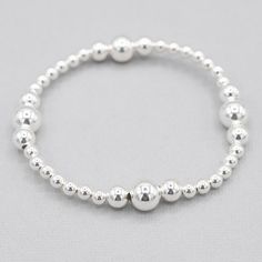 Want to feel instantly pulled together? You've found the perfect bracelet to add to your looks. This "currently classic" style is the answer. It's elevated and yet understated. The stations are precisely set to showcase the larger beads. You'll simply love wearing or gifting! 4mm sterling silver beads with 6 & 8mm larger beads set in four stations around bracelet. Select an all sterling style or mix your metals by adding a gold base. Easy wear and effortless stacking with sturdy stretch cord des Classic Adjustable Sterling Silver Bracelet With Spacer Beads, Classic Bracelets With 8mm Beads For Everyday, Classic Everyday Bracelet With 8mm Beads, Classic Sterling Silver Bracelet With Spacer Beads, Classic Sterling Silver Stretch Bracelet, Classic Adjustable Hypoallergenic Stretch Bracelet, Classic Everyday Bracelets With Polished Beads, Classic Polished Beads Bracelets For Everyday, Classic Sterling Silver Bracelet With Round Beads For Everyday