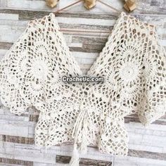 the crocheted top is hanging on a wooden wall