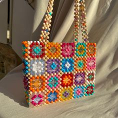 a multicolored beaded purse sitting on top of a white cloth covered chair