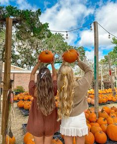 two girls are standing in front of pumpkins