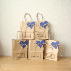 four bags with blue hearts tied to them on a wooden table next to a white wall