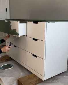 a woman is working on an unfinished cabinet