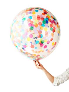 a person holding a large balloon with confetti sprinkles on it