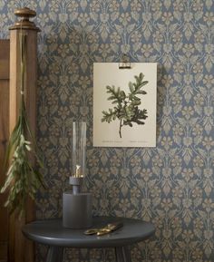 a room with a table, clock and wall paper on the wall next to it