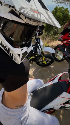 a person wearing a helmet on top of their head next to two parked motorbikes