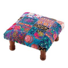 the foot stool is made out of patchwork fabric and wooden legs are decorated with colorful flowers