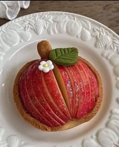 there is a piece of fruit on the plate that looks like an apple with leaves and flowers