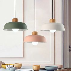 three pendant lights hanging over a table with plates and cups in front of the window