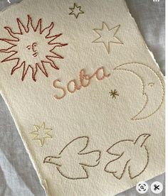 an embroidered piece of cloth with stars and the word sora written in gold on it