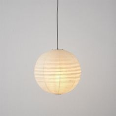 a white lamp hanging from a ceiling in a room with gray walls and flooring