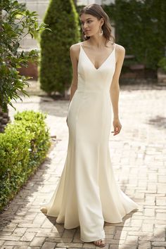 a woman in a white dress walking down a brick walkway