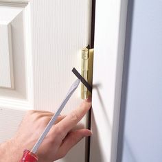 a person holding a pair of scissors in front of a door with the handle missing