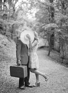 a man and woman kissing in the woods with suitcases under their arms, black and white photo