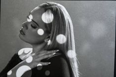 a black and white photo of a woman with polka dots on her face