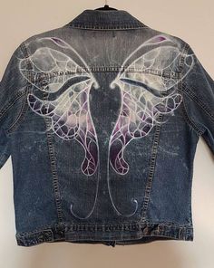 the back of a jean jacket with wings painted on it