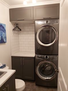 a washer and dryer in a small room next to a sink with cabinets