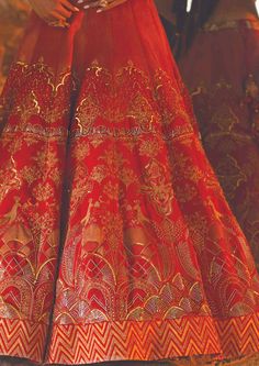 This dreamy lehenga features hand embroidery and gold printing. The blouse comes with a v neckline with floral motifs on it. A bridal wear lehenga that gives an exquisite look to you, bathed in wedding vibes. Festive Gown With Gold Embroidery For Traditional Ceremonies, Festival Lehenga With Gold Embroidery For Traditional Ceremonies, Gold Embroidered Dupatta For Traditional Ceremonies, Red Lehenga With Gold Embroidery For Festivals, Red Lehenga With Gold Embroidery For Reception, Traditional Lehenga With Gold Embroidery For Reception, Gold Lehenga With Resham Embroidery For Traditional Ceremonies, Gold Lehenga With Intricate Embroidery For Traditional Ceremonies, Red Lehenga With Gold Embroidery For Wedding