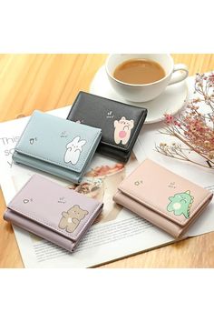 four small wallets sitting on top of a table next to a cup of coffee