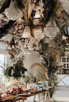 a dining room filled with lots of tables covered in plants and hanging lights over them