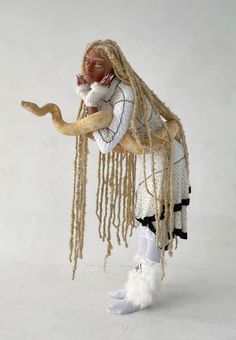 a woman with long blonde hair holding a snake in her arms and wearing white boots