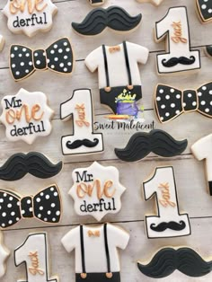 decorated cookies are arranged in the shape of mustaches, bow ties and shirts on display