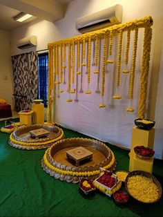 an arrangement of desserts on display in front of a wall with yellow ribbons and decorations