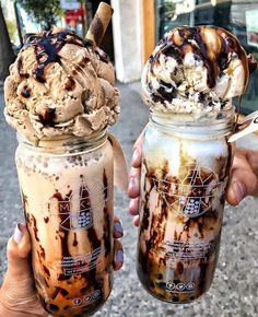 two people holding up mason jars filled with ice cream and caramel flavored milkshakes