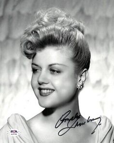 an old black and white photo of a woman in a dress smiling at the camera