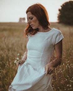 a woman in a white dress standing in a field