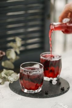 two glasses filled with red liquid being poured into them