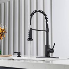 a kitchen faucet with water running from it's spout, in front of a white counter top