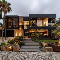 a modern home with stone steps leading to the front door and patio area, surrounded by palm trees