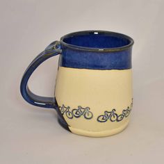 a blue and white coffee mug with an ornate design on the outside, sitting on a table