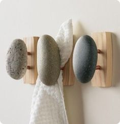 three rocks are mounted to the wall with towel holders on it and one rock is in between two wooden hooks