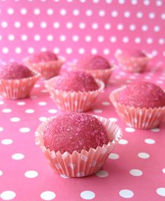 pink cupcakes are lined up on a polka dot tablecloth