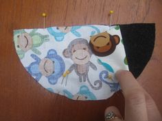 someone is sewing something on top of a cloth with monkey and monkey faces on it